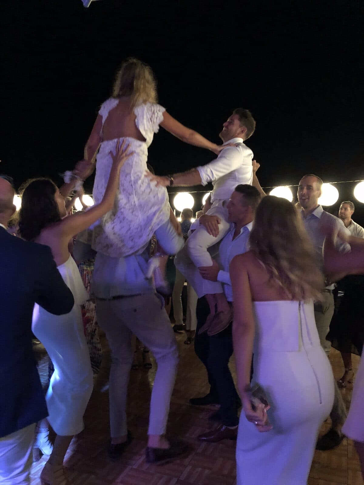 Bride and groom lifted on shoulders in celebration