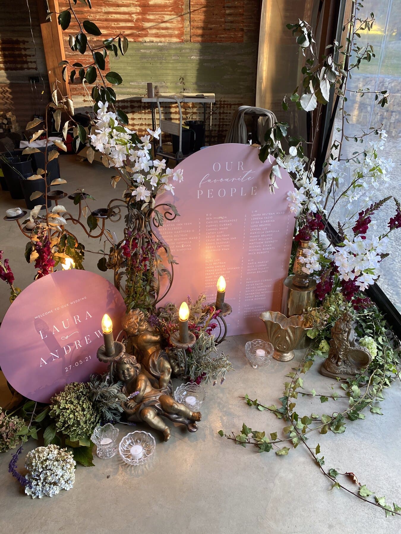 Pink seating chart and the LAURA & ANDREW sign greeting guests at the entrance